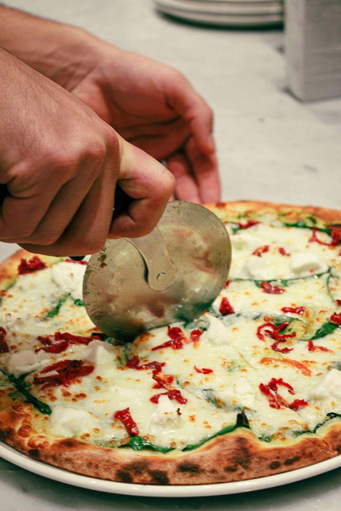 category-02 Close-up of a delicious homemade pizza being sliced with a pizza cutter, showcasing cheese and toppings.